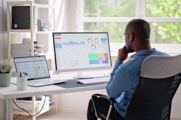 Man analyzing performance metrics on multiple screens at his desk