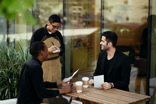 Waiter taking orders from two customers at an outdoor café