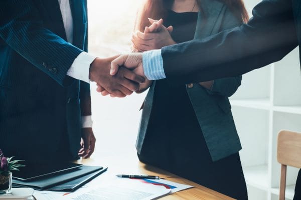 Business professionals shaking hands over a desk, symbolizing agreement or partnership.