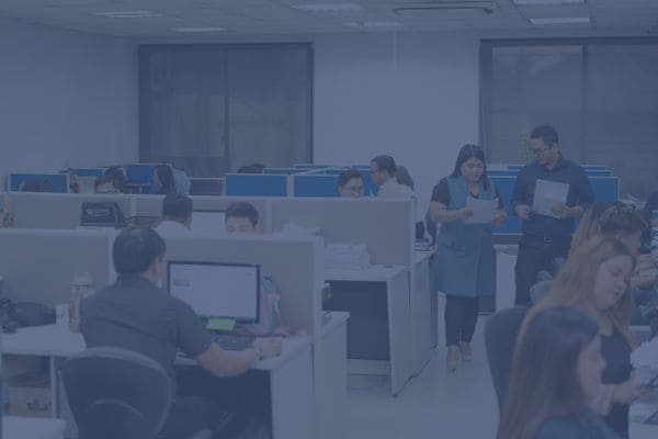 Office employees working and collaborating at their desks in a busy workspace.