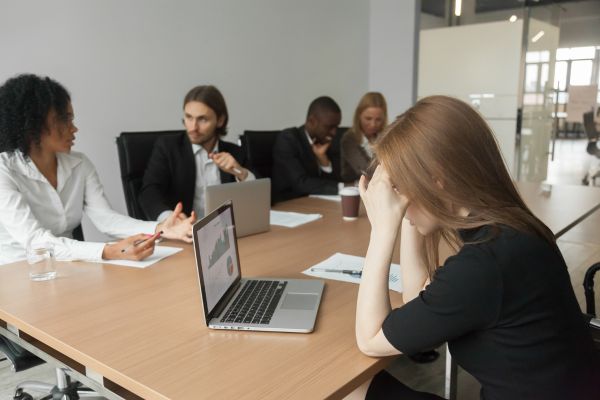 A woman at a table, head in hands, contemplates the complexities of hiring challenges and opportunities.